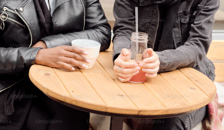 Dos personas sentadas frente a frente en un ambiente relajado, conversando de manera tranquila y sonriente, simbolizando el proceso de coaching personalizado