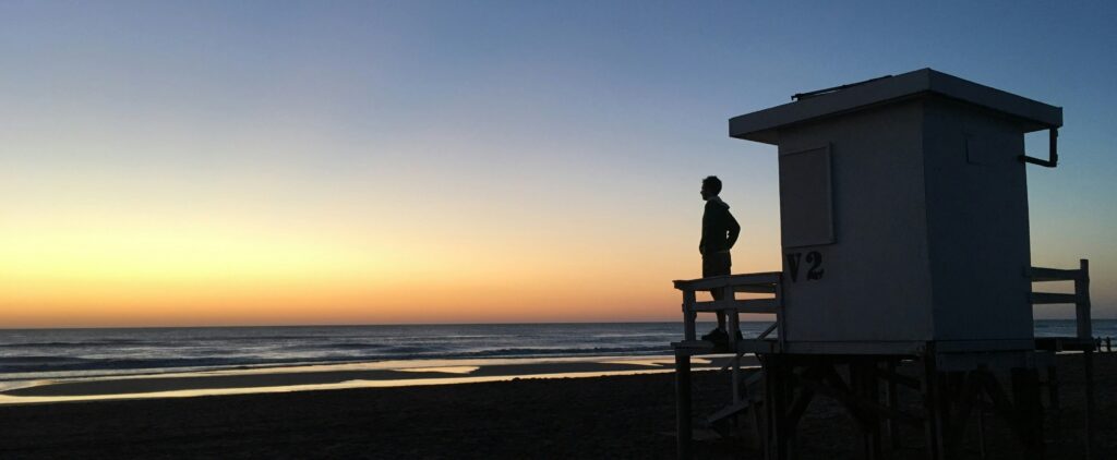 Persona de pie en un mirador al amanecer, contemplando un paisaje amplio y lleno de luz, simbolizando nuevas oportunidades y claridad