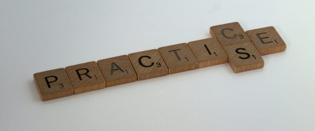 Fichas del juego Scrabble que forman la palabra "PRACTICE" sobre una superficie lisa.