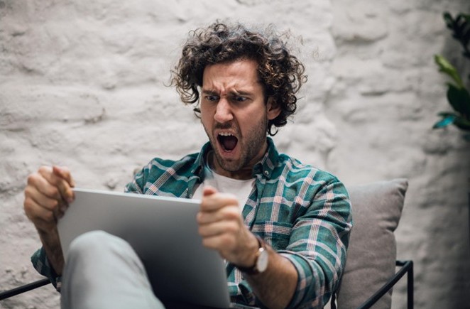 Persona frente a una pantalla con expresión de frustración y agobio, simbolizando emociones negativas causadas por la tecnología y la inteligencia artificial.